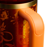Stanley x Karol G 40 oz Quencher Tumbler in ruby red with floral artwork and pineapple straw topper next to its orange collector box - View 5 | Clistos