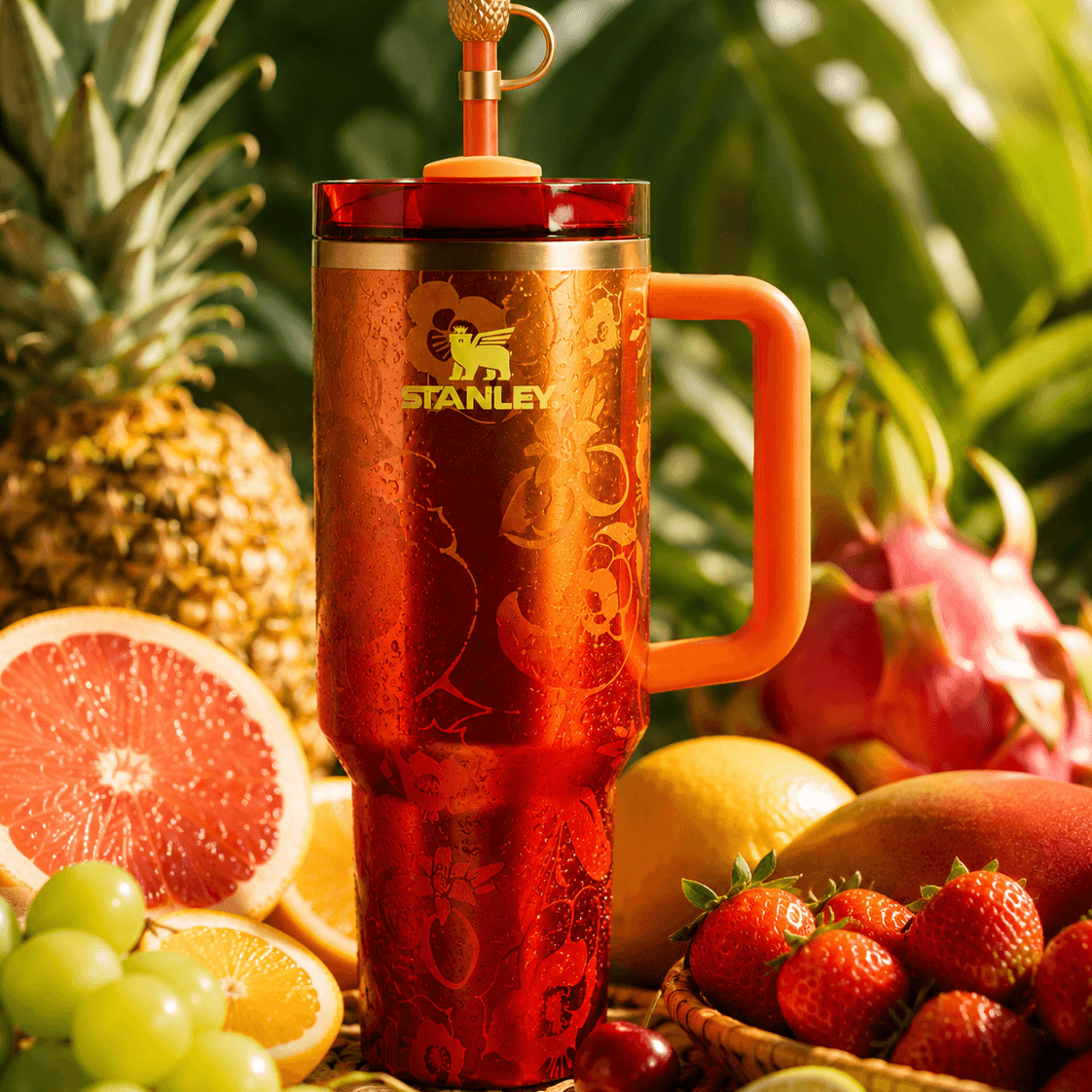 Stanley x Karol G 40 oz Quencher Tumbler in ruby red with floral artwork and pineapple straw topper next to its orange collector box - View 10 | Clistos