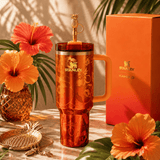 Stanley x Karol G 40 oz Quencher Tumbler in ruby red with floral artwork and pineapple straw topper next to its orange collector box - View 1 | Clistos